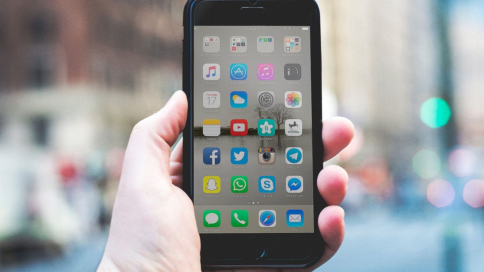 Loş bir ortamda elinde telefon tutan biri; ekranın ışığı yüzüne vuruyor